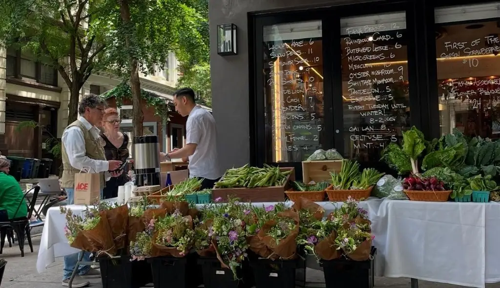 A neighborhood market with flowers and fresh produce on a New York City street